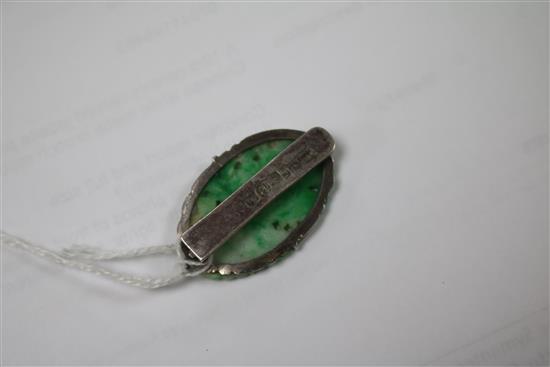 A 19ct century carved jadeite plaque, in later Chinese white metal brooch mount, 36mm.